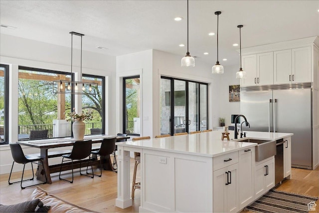 kitchen featuring a sink, light wood-style flooring, light countertops, white cabinets, and appliances with stainless steel finishes