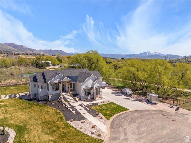 view of front of home featuring a front lawn, a mountain view, fence, and concrete driveway
