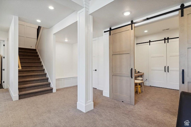 basement with carpet, a barn door, and recessed lighting