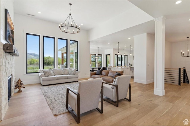 living room with baseboards, recessed lighting, a notable chandelier, and light wood-type flooring