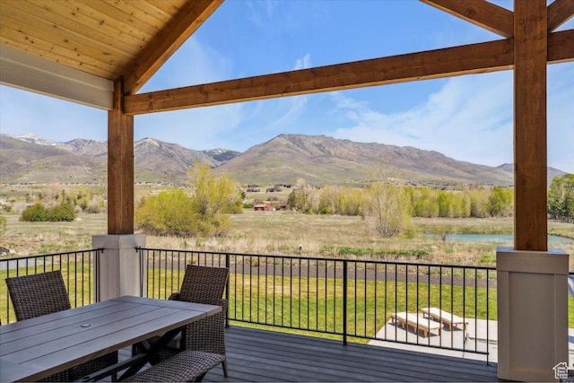 deck with a water and mountain view and outdoor dining space