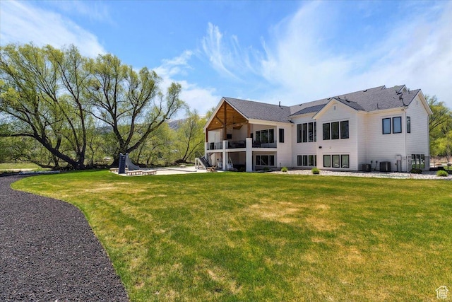 rear view of house featuring a lawn, a balcony, and central air condition unit