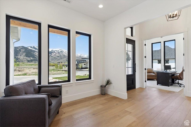 living area with baseboards, a notable chandelier, light wood finished floors, and recessed lighting