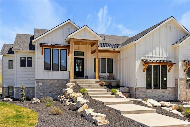 view of front of property with board and batten siding, roof with shingles, and stone siding