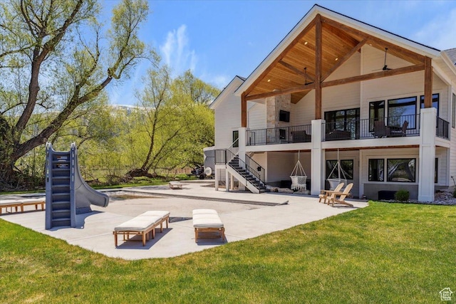 back of property featuring a yard, a patio area, stairs, and a balcony