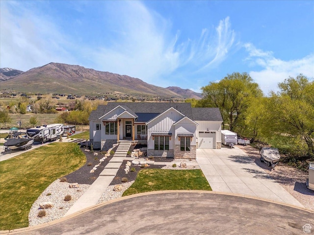 view of front facade featuring board and batten siding, a mountain view, an attached garage, concrete driveway, and stone siding