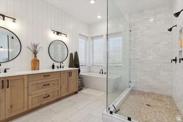 full bathroom featuring a sink, a freestanding bath, double vanity, and a shower stall