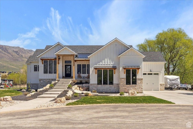 view of front of home with board and batten siding, driveway, an attached garage, a shingled roof, and stone siding