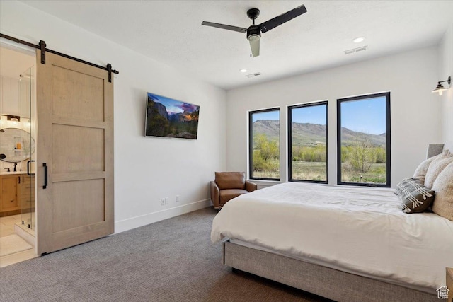 bedroom featuring visible vents, a barn door, baseboards, and carpet floors