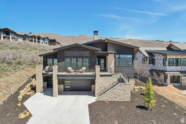 11332 N White Tail Ct Unit 30, Hideout, UT 84036 - view of front of house with an attached garage, a mountain view, stone siding, a chimney, and concrete driveway