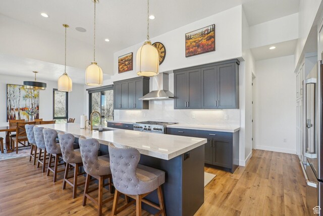 11332 N White Tail Ct Unit 30, Hideout, UT 84036 - kitchen with wall chimney range hood, tasteful backsplash, a kitchen breakfast bar, and light wood-style flooring