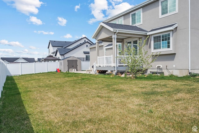 back of property featuring a storage shed, stucco siding, an outbuilding, a fenced backyard, and a lawn