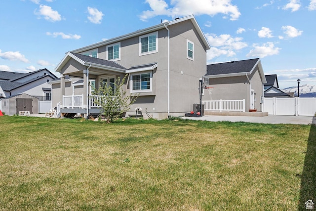rear view of property with fence, a storage shed, an outdoor structure, stucco siding, and a lawn