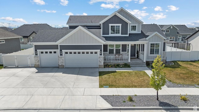 view of front facade with board and batten siding, covered porch, concrete driveway, a front yard, and a gate
