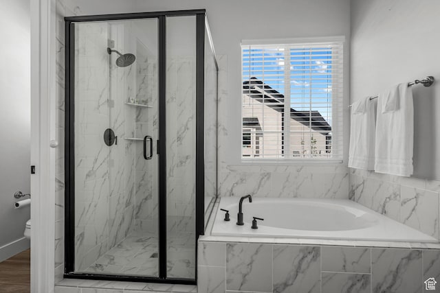 full bath with a marble finish shower, a wealth of natural light, a garden tub, and toilet