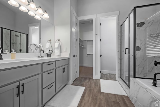 bathroom featuring a stall shower, a spacious closet, double vanity, and wood finished floors