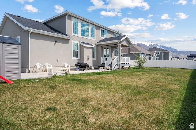 rear view of house featuring a mountain view, a patio area, stucco siding, and a lawn