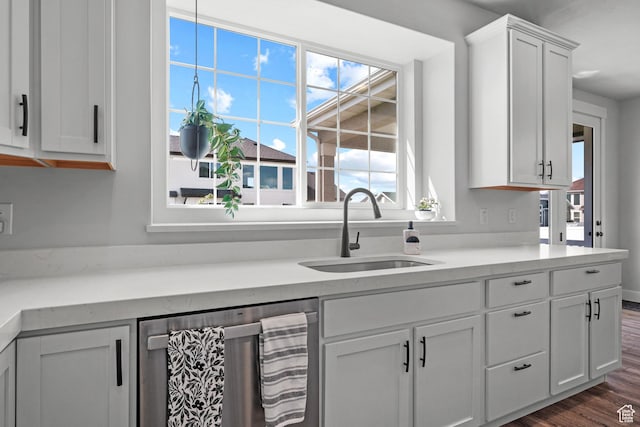 kitchen with a sink, dark wood finished floors, white cabinetry, stainless steel dishwasher, and light countertops