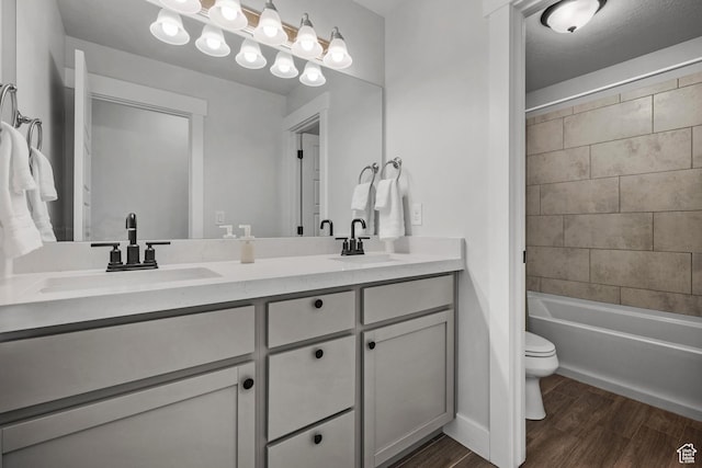 full bath with double vanity, toilet, wood finished floors, and a sink