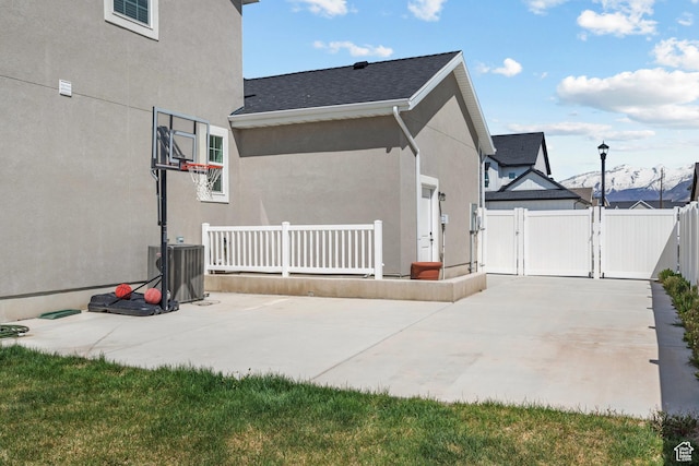 view of home's exterior with a gate, a patio area, stucco siding, and central AC