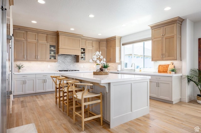 kitchen featuring light wood finished floors, light countertops, a center island, a kitchen bar, and recessed lighting