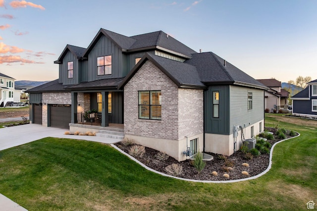 view of front of home with board and batten siding, concrete driveway, a front yard, brick siding, and covered porch
