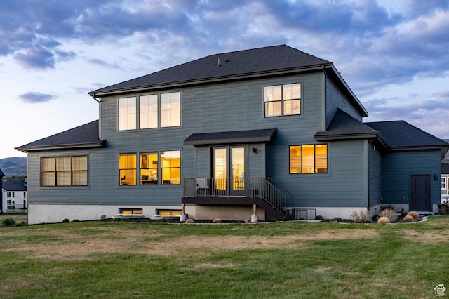 rear view of property featuring a lawn and roof with shingles