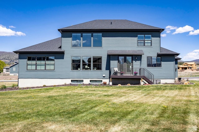 back of house featuring a yard and a shingled roof