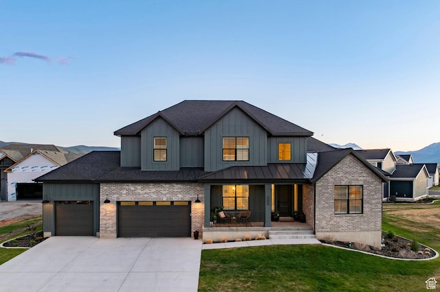 view of front of property featuring brick siding, a porch, a front yard, driveway, and board and batten siding