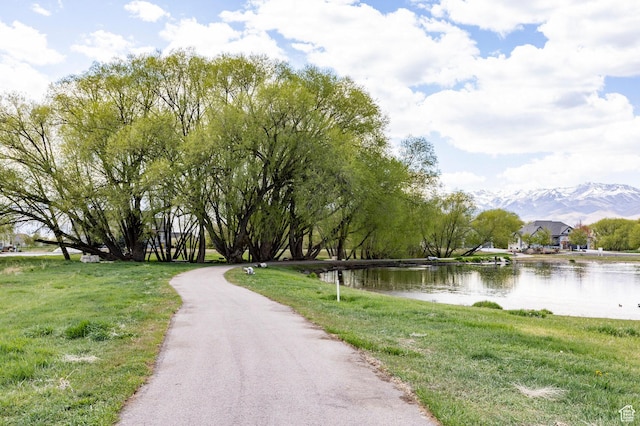 surrounding community with a water view and a yard