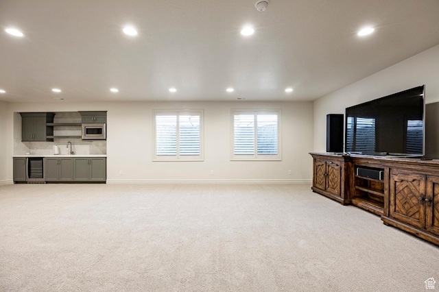 unfurnished living room featuring baseboards, light carpet, recessed lighting, and a sink