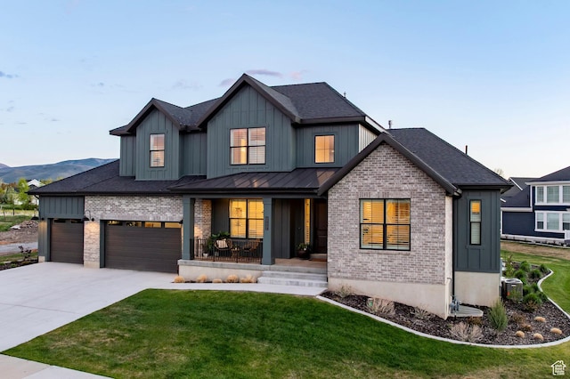 modern farmhouse with covered porch, brick siding, board and batten siding, driveway, and a front yard