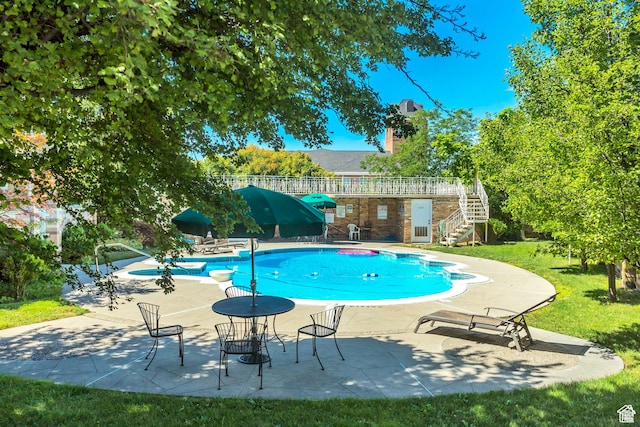 outdoor pool featuring a yard, stairway, and a patio