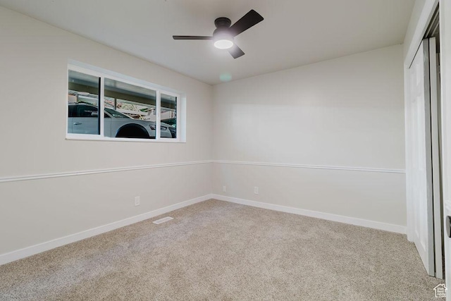 empty room with carpet flooring, baseboards, a ceiling fan, and visible vents