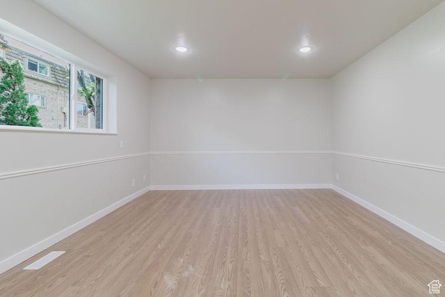 empty room with baseboards, light wood-type flooring, and recessed lighting