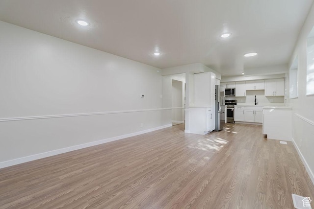 unfurnished living room with recessed lighting, baseboards, light wood finished floors, visible vents, and a sink