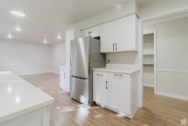 kitchen featuring freestanding refrigerator, light wood-style flooring, white cabinetry, and light countertops