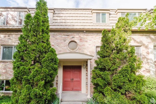 property entrance featuring brick siding and mansard roof
