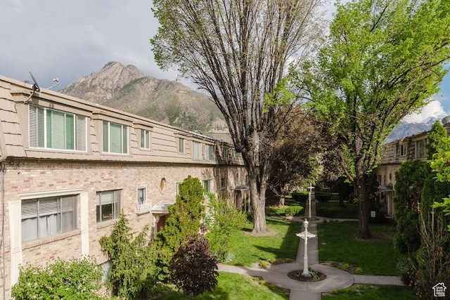 view of side of property featuring a yard, brick siding, and a mountain view