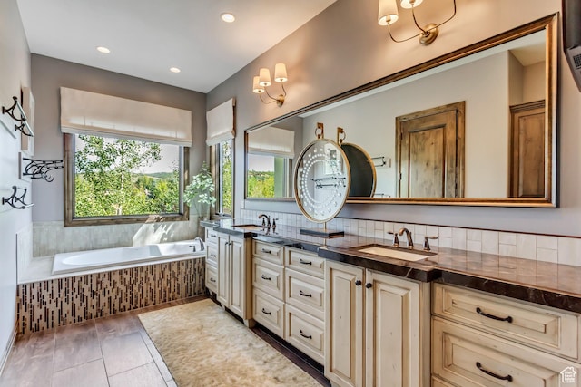 bathroom with recessed lighting, double vanity, a bath, and a sink