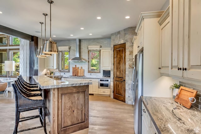 kitchen with wall chimney range hood, backsplash, recessed lighting, and appliances with stainless steel finishes