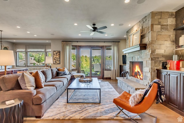 living room with ceiling fan, a fireplace, light wood-style flooring, and recessed lighting
