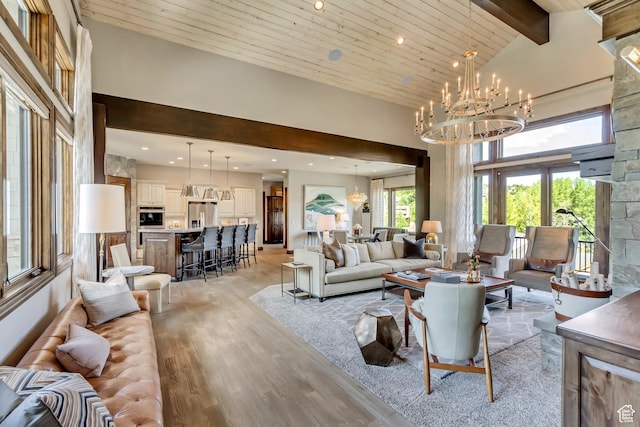 living room with an inviting chandelier, light wood-style flooring, a towering ceiling, beamed ceiling, and recessed lighting