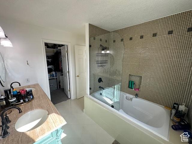 full bathroom featuring tile patterned flooring, tiled shower / bath combo, a spacious closet, a textured ceiling, and vanity
