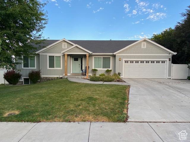 single story home featuring an attached garage, concrete driveway, a front yard, and board and batten siding