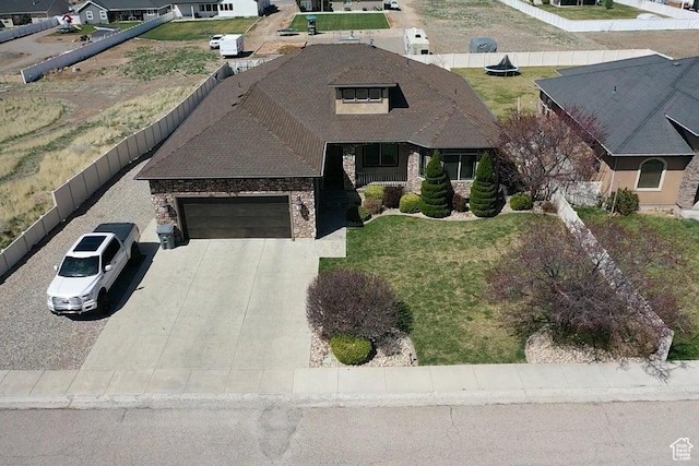 view of front of house with driveway, brick siding, fence, a garage, and stone siding