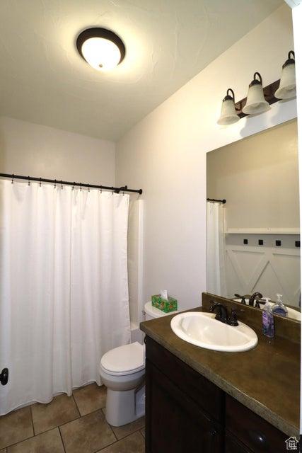 full bath with toilet, curtained shower, tile patterned flooring, and vanity
