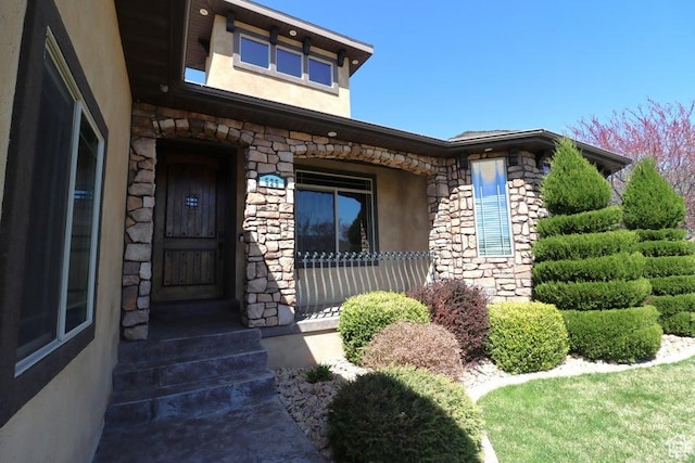 view of exterior entry featuring stucco siding and stone siding