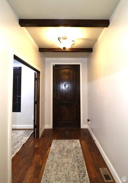 doorway to outside with baseboards, beamed ceiling, dark wood finished floors, and visible vents