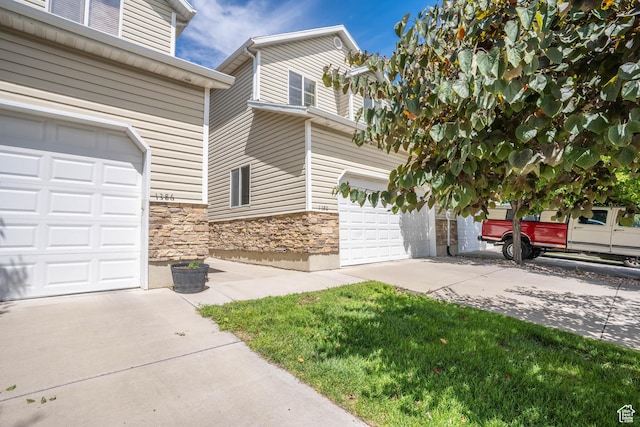 exterior space with stone siding, driveway, and a garage